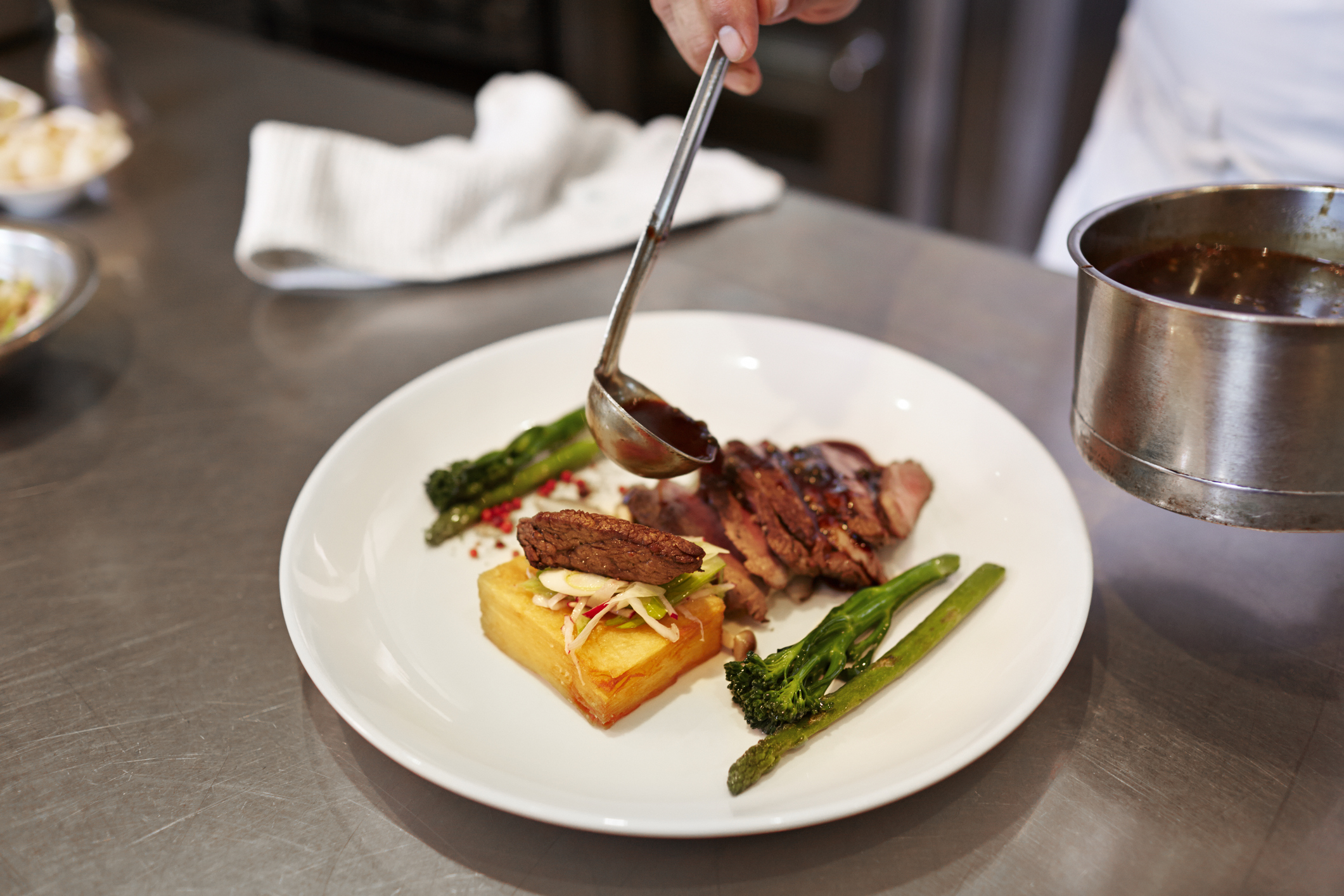 Chef pouring sauce on dish in the kitchen