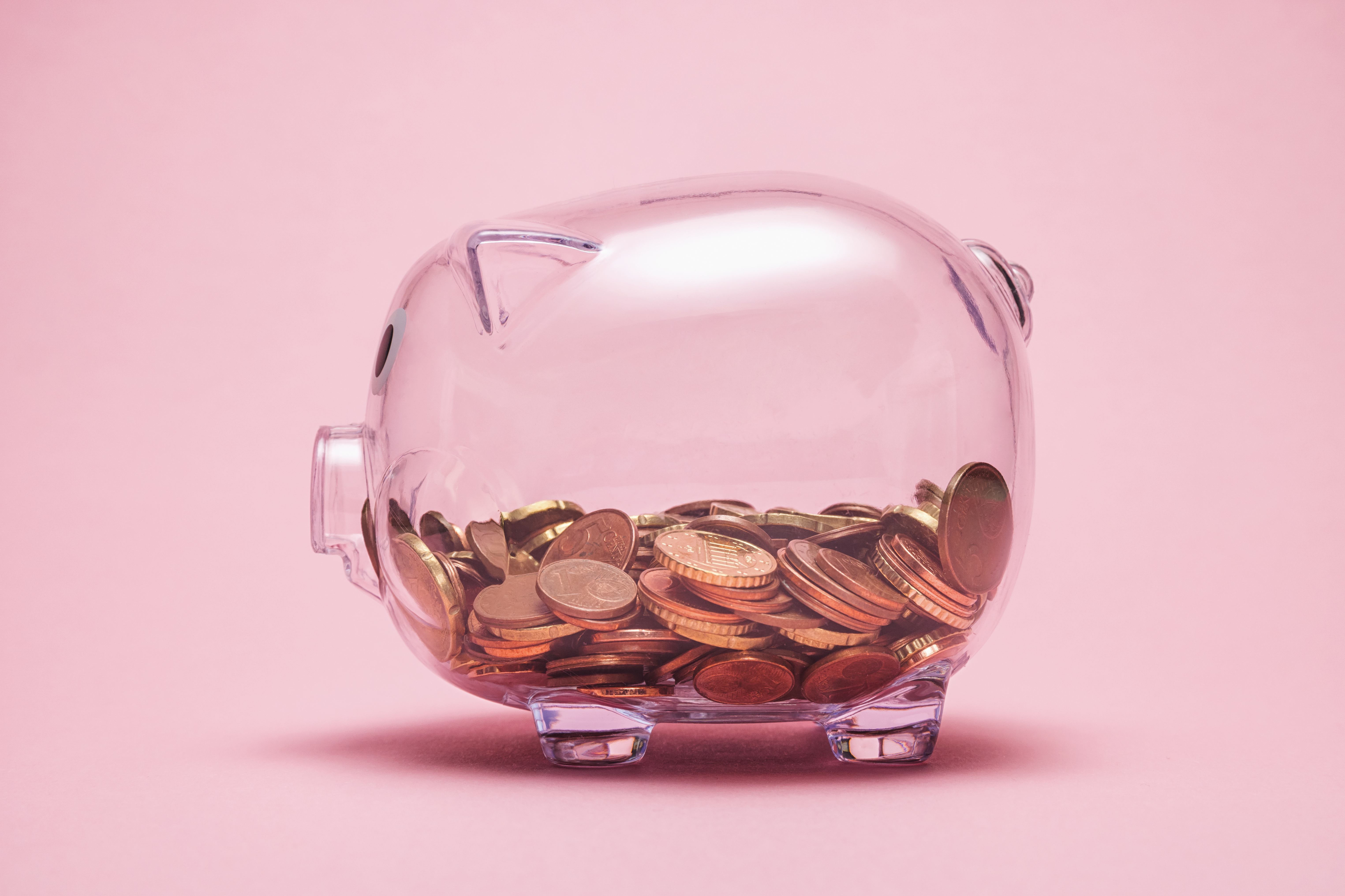 Close-Up Of Coin In Piggy Bank Against Pink Background